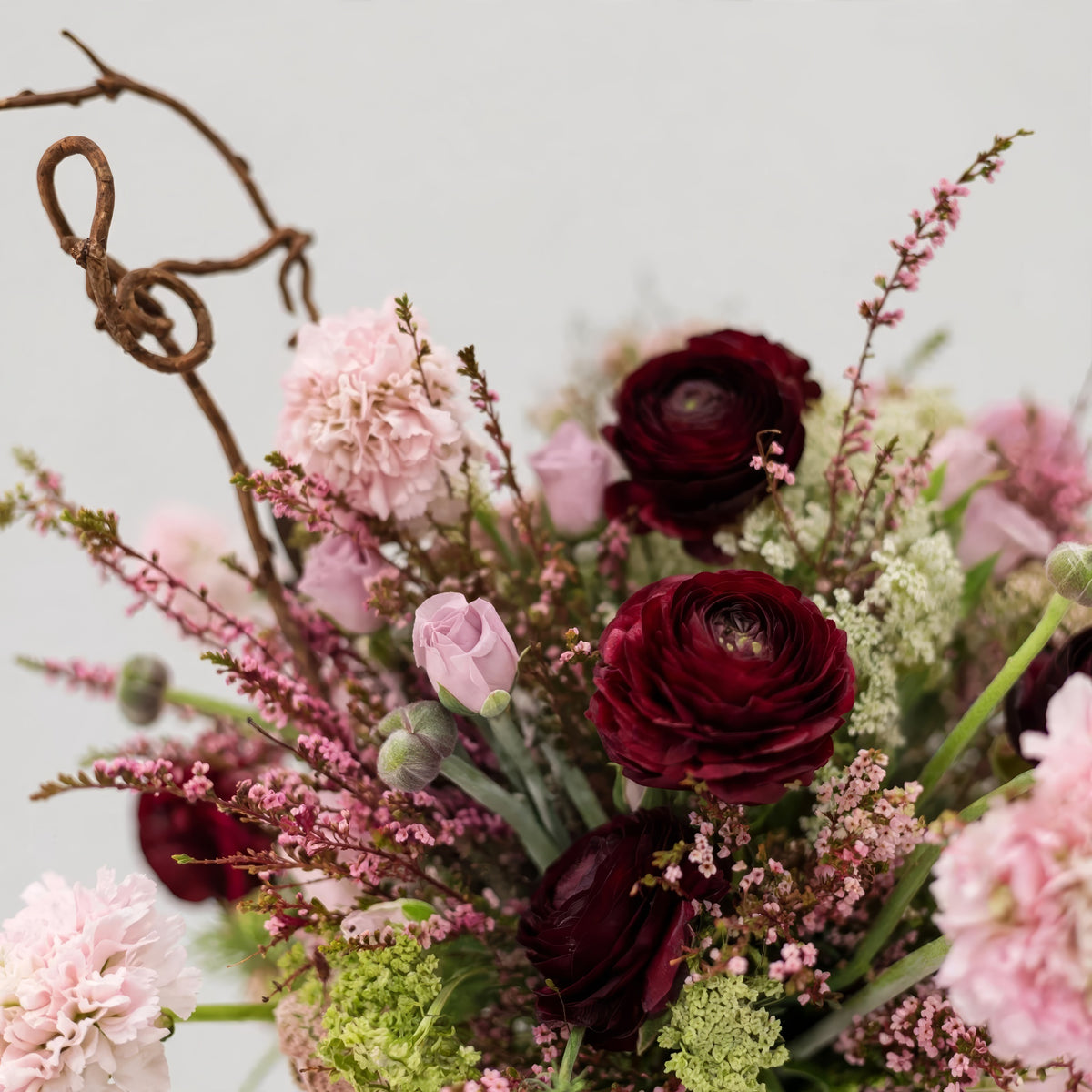 Close-up of Blush Nocturne showing burgundy ranunculus, soft blush pink blooms, delicate filler flowers and greenery.