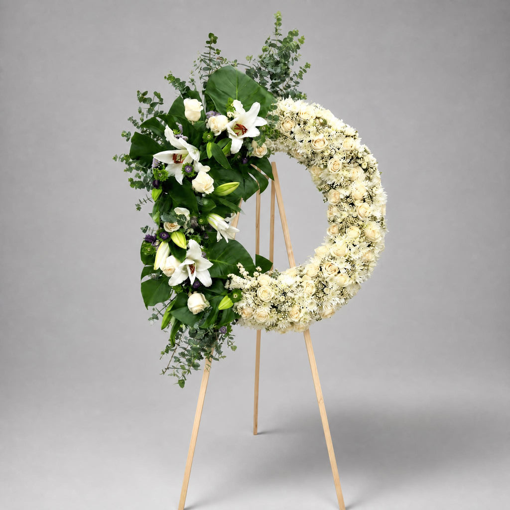 Floral wreath with white flowers and greenery on a gray background