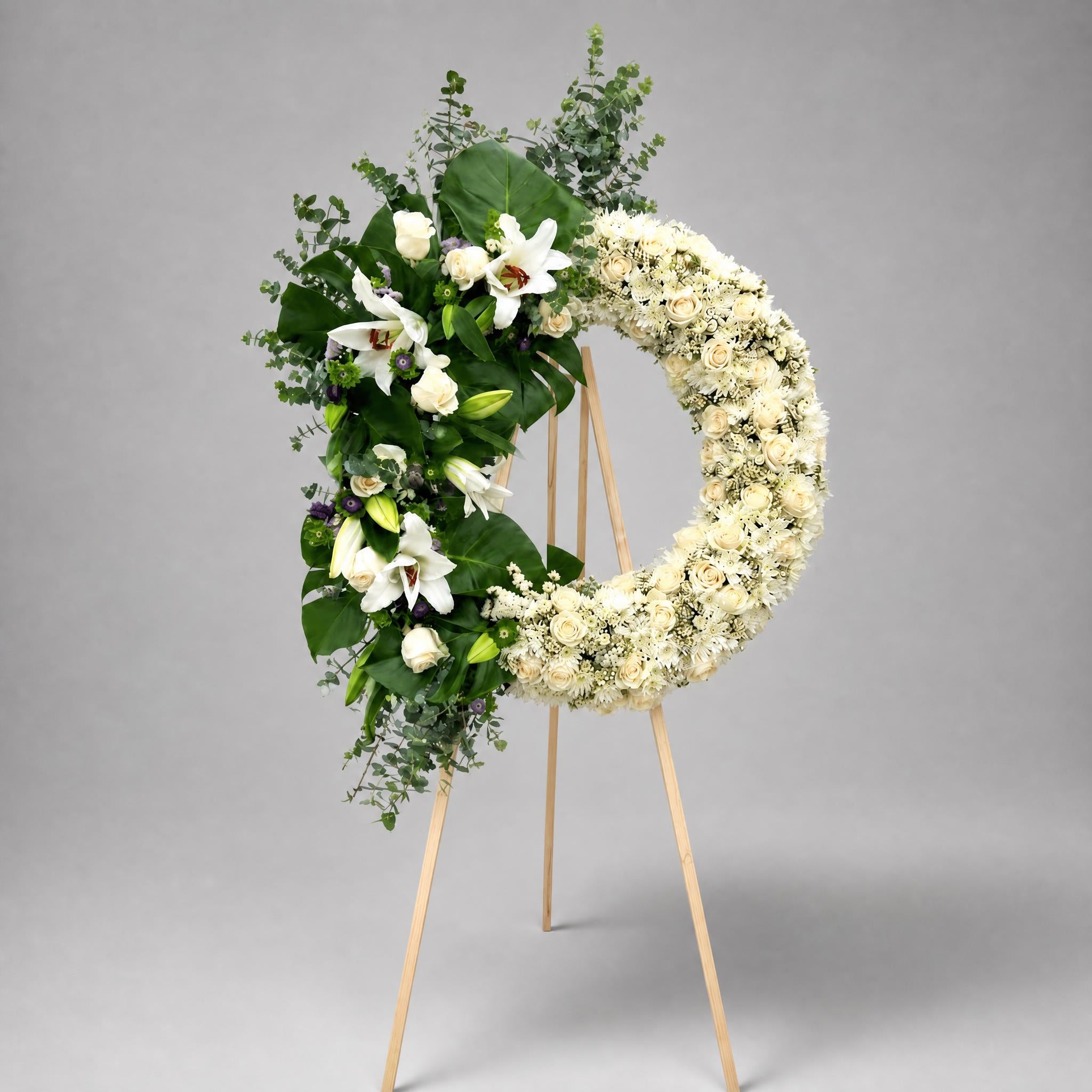 Floral wreath with white flowers and greenery on a gray background