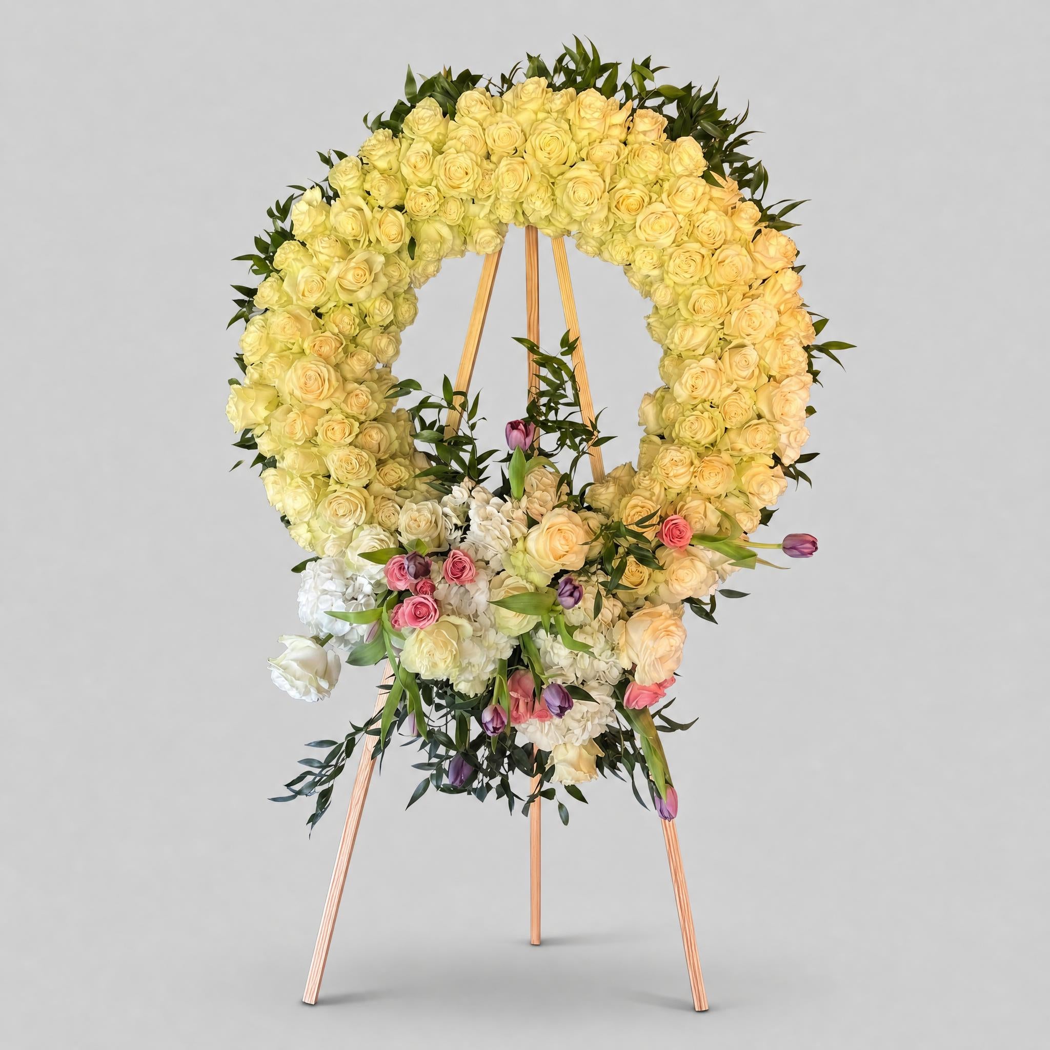 Floral wreath with yellow roses and greenery on a gray background