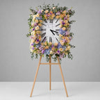 Floral arrangement in the shape of a clock on a stand against a gray background