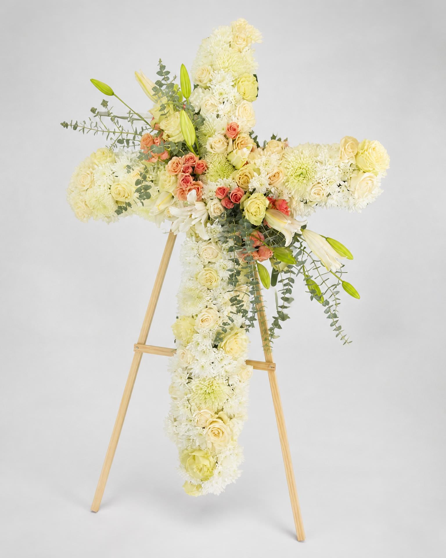 Floral cross arrangement on a stand against a light gray background